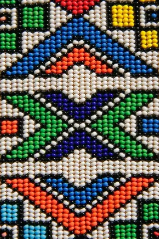 Colorful beaded mosaic wallpaper with geometric tribal patterns in blue, orange, green, and cream beads