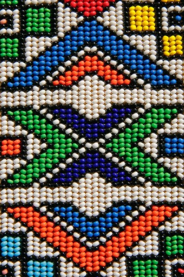 Colorful beaded mosaic wallpaper with geometric tribal patterns in blue, orange, green, and cream beads