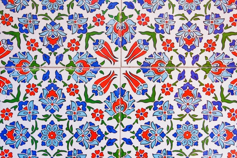 Repeating Turkish tile pattern with blue, red and green flowers and geometric shapes on white background