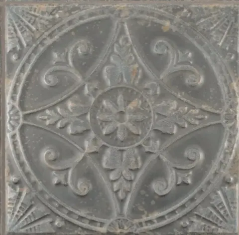 Grey stone tile with ornate carved medallion, scrolls, and central floral design