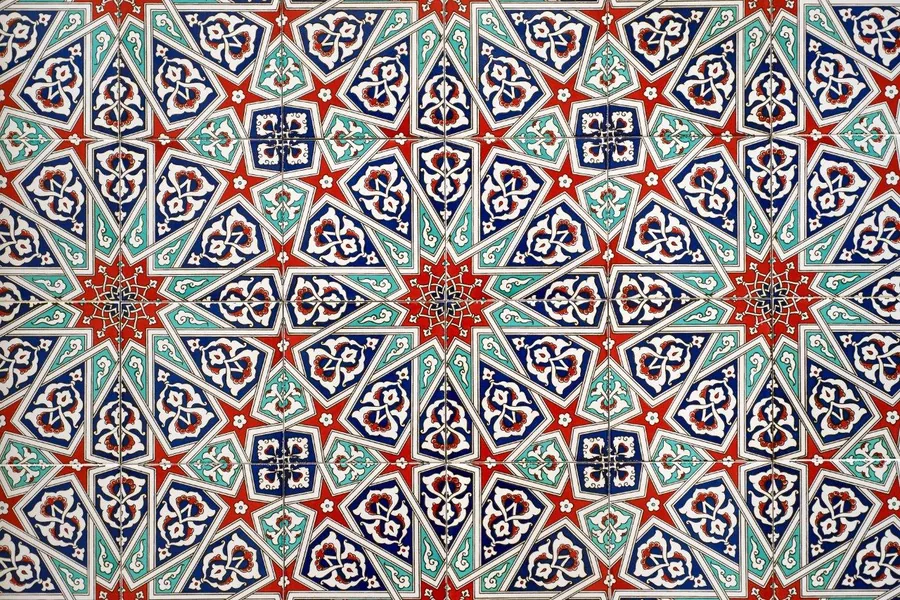 Repeating geometric mosaic tile pattern with red stars and ornate navy and turquoise floral medallions