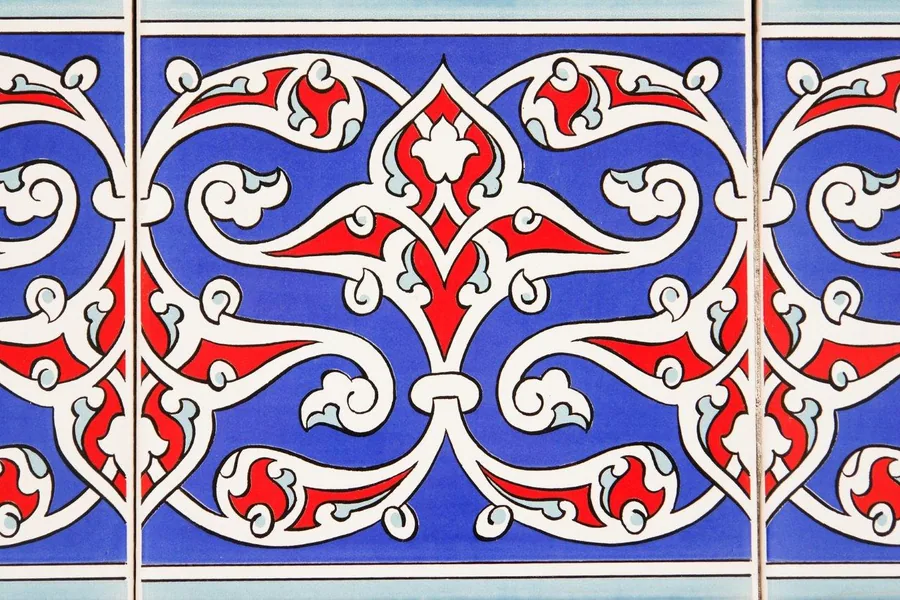 Repeating ornate damask pattern in red, white and blue with symmetrical scrollwork and floral motifs