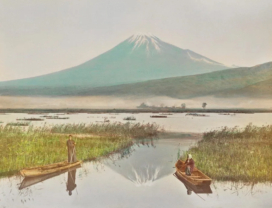 Traditional Japanese landscape with Mount Fuji, wooden boats on misty lake, and golden reeds in foreground.