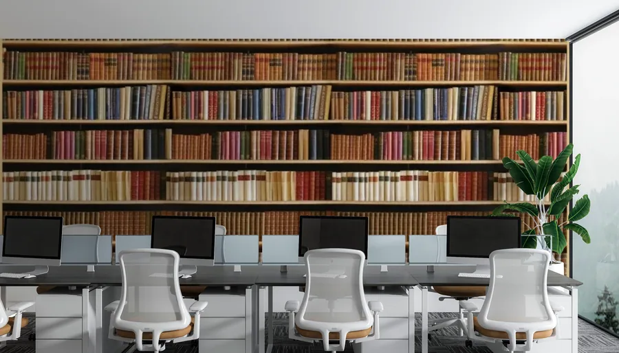 Wall mural of a wooden bookshelf filled with colorful vintage books in an office setting with white desk chairs.