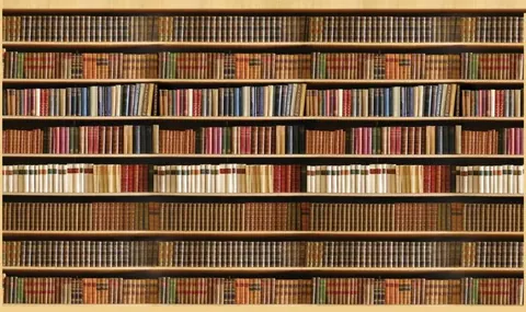 Wooden bookshelf wall with rows of vintage books in brown, tan, red, and cream tones.
