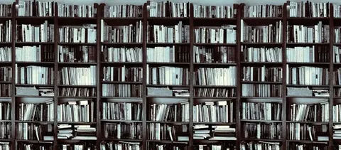 Repeating pattern of dark brown wooden bookshelves filled with white and cream books.