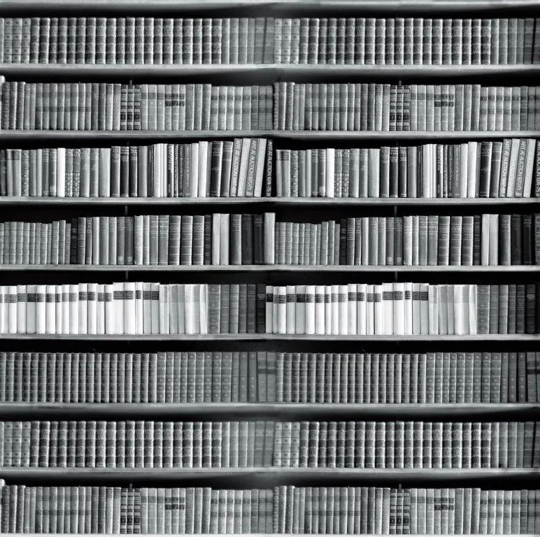 Black and white repeating pattern of book spines on shelves creating a library wall texture.