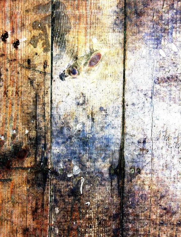 Distressed wooden planks with varied stains, knots, and weathered texture in warm and cool tones.