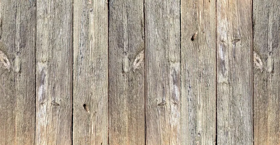 Close-up of weathered wooden planks with natural grain patterns and knots in grey and brown tones.