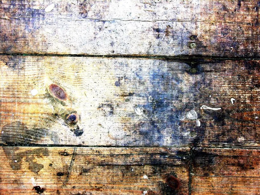 Aged wooden planks with weathered blue and brown stains, knots, and distressed surface texture