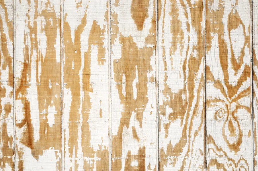 Weathered white and tan wooden planks with peeling paint and natural grain texture