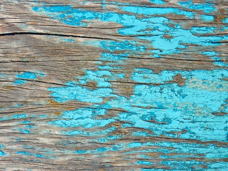 Distressed turquoise paint on weathered wooden planks with natural wood grain showing through