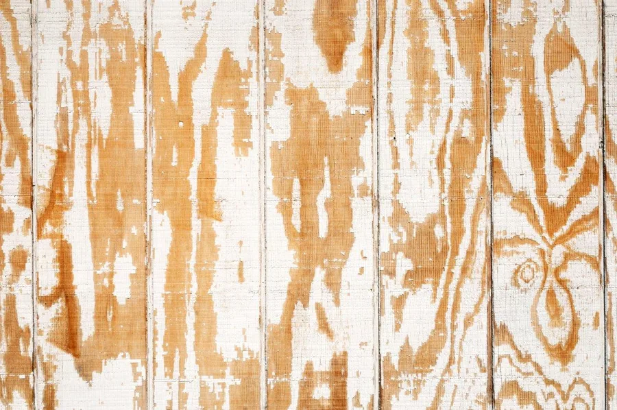 Weathered white painted wood planks with peeling finish and natural wood grain showing through.